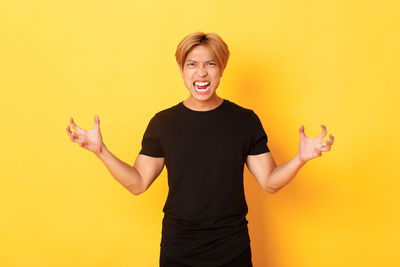 Portrait of smiling woman standing against yellow background