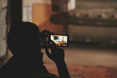 Rear view of man photographing at night