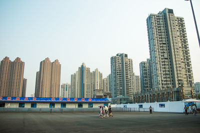 People on street by buildings against sky