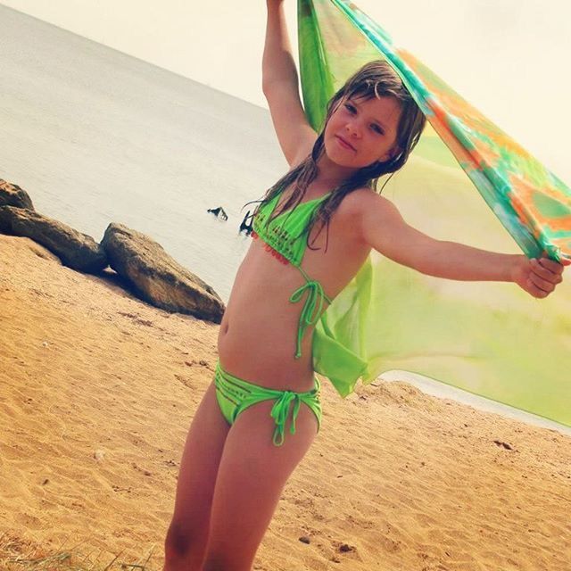 YOUNG WOMAN STANDING ON BEACH