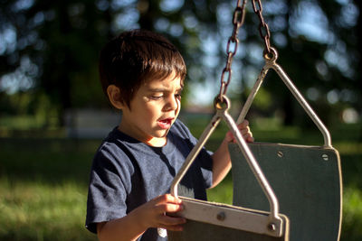 Cute boy looking at swing while standing on playground