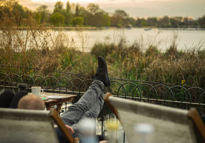 Man resting while relaxing legs on railing by river