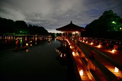 Illuminated pier over sea against sky at night