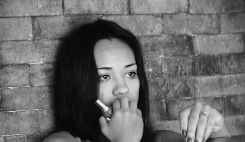 Portrait of young woman against wall