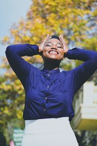 Portrait of smiling young woman standing against trees