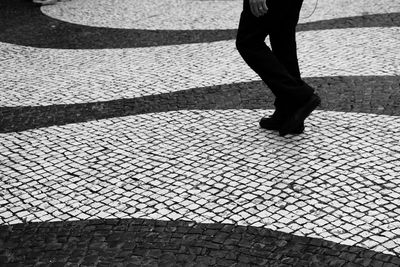 Low section of man walking on cobblestoned walkway