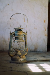 Close-up of old lantern on table against wall