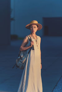 Portrait of young woman wearing hat standing against sky