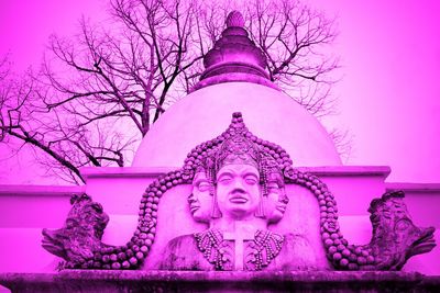 Low angle view of statue against bare trees against sky