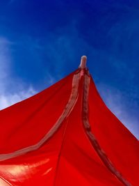 Low angle view of red umbrella against blue sky