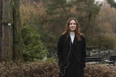 Portrait of smiling young woman standing in forest