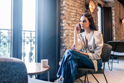 Young woman sitting on table at home