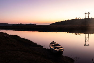 Calm lake with traditional wood boat and dramatic sunrise colorful sky reflection at morning