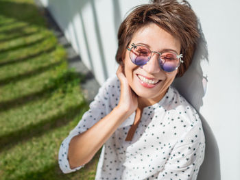 Smiling woman in colorful sunglasses on lawn in urban park.relax outdoors after work.summer vibes.