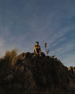 Low angle view of woman sitting on rock