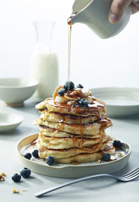 Stack of blueberry banana walnut pancakes with syrup pouring breakfast