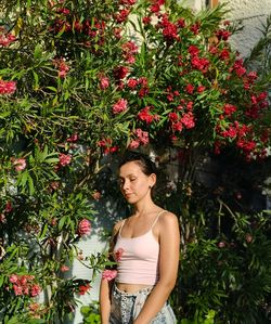 Beautiful young woman standing by flowering plants