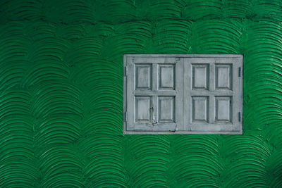 Closed window on green wall