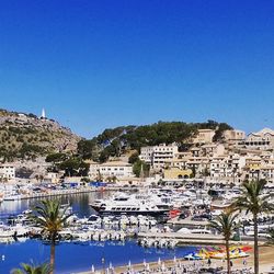 Boats in harbor against clear blue sky