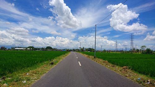 Road amidst field against sky