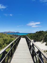 Bridge over calm blue sea against sky