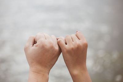 Cropped hand of couple holding little finger outdoors