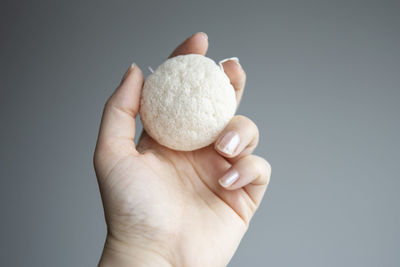 Close-up of hand holding apple against white background