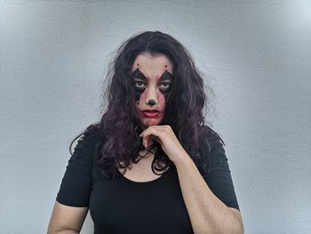 Portrait of young woman with face paint against wall