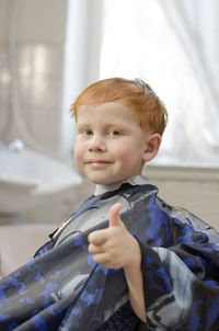 Red-haired four-year-old boy smiling at the barbershop. joyful child in the barbershop