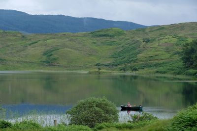 Scenic view of lake by mountain against sky