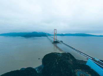 Suspension bridge over sea against sky