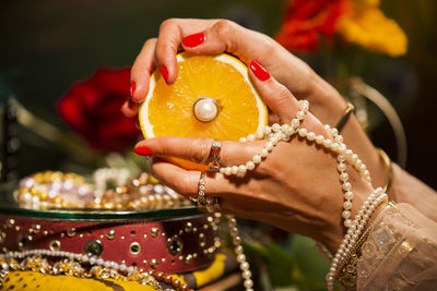 Cropped hand of woman wearing jewelry holding orange