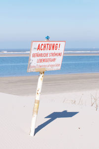 Information sign on beach against sky