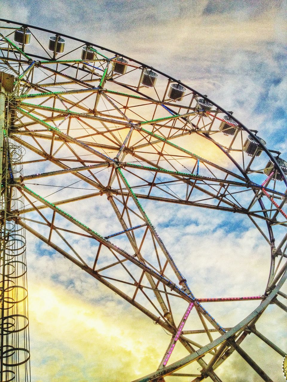 sky, low angle view, amusement park, ferris wheel, cloud - sky, metal, amusement park ride, built structure, cloudy, arts culture and entertainment, metallic, cloud, architecture, day, outdoors, silhouette, connection, no people, dusk, nature