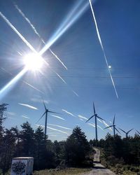 Low angle view of vapor trails against sky on sunny day