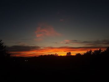 Silhouette landscape against orange sky