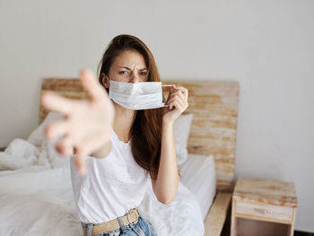 Portrait of beautiful young woman sitting on bed at home