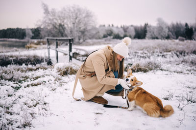 Rear view of man with dog on snow covered field