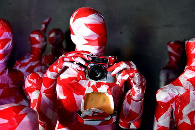 Mannequins covered in red and white plastic holding camera