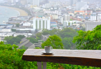Coffee cup on table against buildings in city