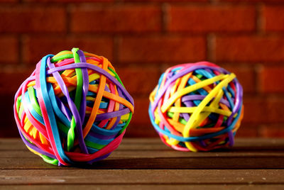 Close-up of colorful rubbers on wooden table against brick wall