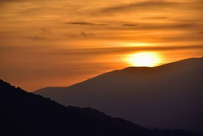 Scenic view of silhouette mountains against romantic sky at sunset