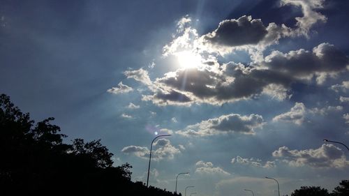 Low angle view of trees against cloudy sky