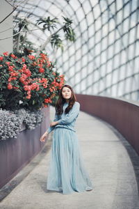 Full length portrait of woman standing by potted plants