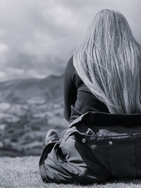 Rear view of woman sitting on a mountain against sky