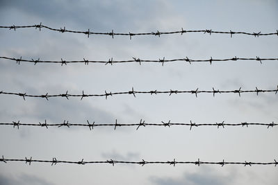 Low angle view of barbed wire fence against clear sky