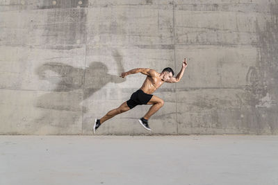 Muscular shirtless man running outdoors