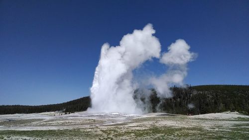 Geyser on field against clear blue sky