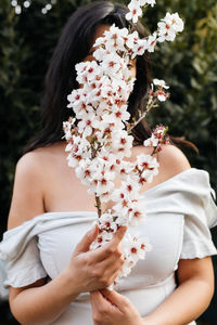 Midsection of woman holding white flowering plant