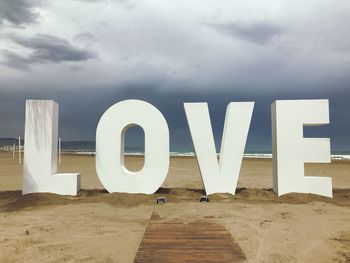 Text on beach against sky